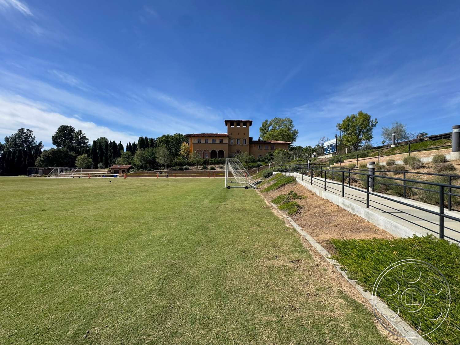 School 20 - exterior, flat roof, metal railing, landscaped lawn, concrete walkway, brick building, arced windows, decorative landscaping, soccer field, open green space, sunny outdoor setting, terracotta tile roofing, two-story architecture, hardwood trees