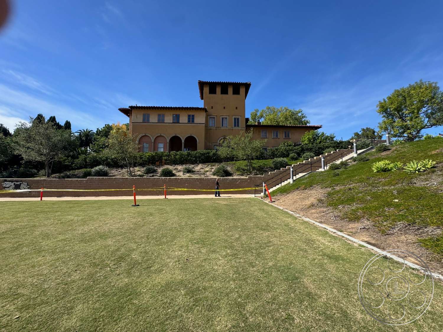 School 20 - exterior, landscaped garden, surrounding greenery, Mediterranean architecture, terracotta roof tiles, stucco walls, arched doorways, hillside location, balcony with wrought iron railings, two-story home, flat lawn area, classical column details, stone pathway steps, stairs with concrete risers