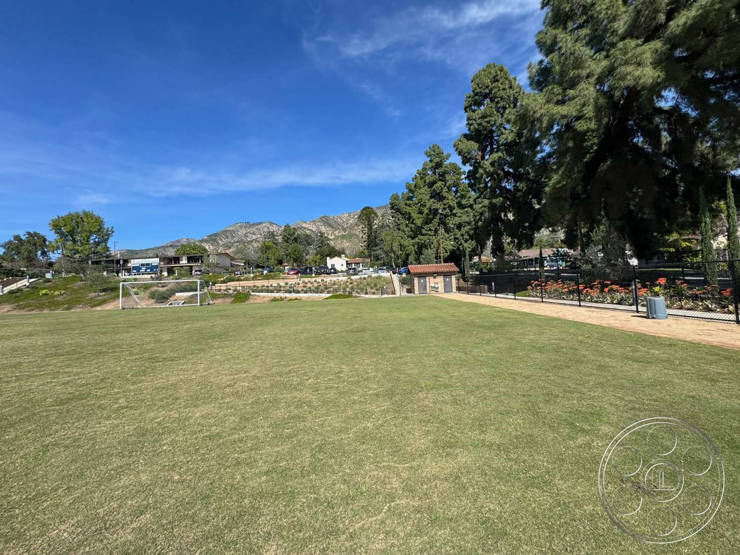 School 20 - exterior, fenced area, mountain backdrop, shade trees, flower garden, urban park environment, hardscape pathway, landscape setting, grass soccer field, park amenities, multi-use recreational area
