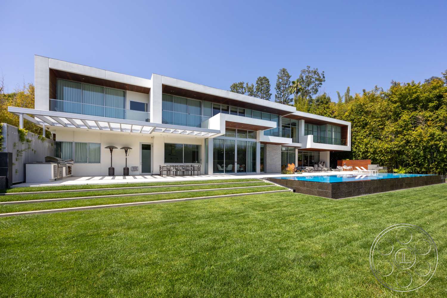 Modern 14 - exterior, glass sliding doors, rectangular swimming pool, modern architectural style, minimalist landscaping, sliding glass windows, two-story home, flat roof design, stucco exterior walls, wood pergola structure, concrete patio floor, steel outdoor furniture, wood deck surrounding pool, landscaped green lawn, stone pool edge