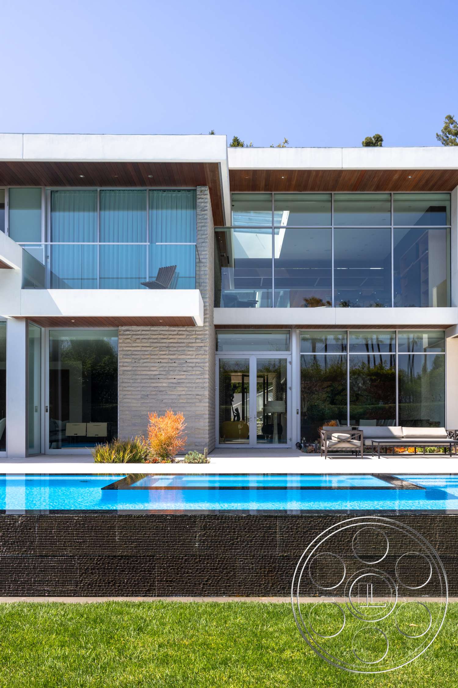 Modern 14 - large windows, exterior, modern architecture, flat roof, minimalist design, stone accent wall, sliding glass doors, rectangular swimming pool, grass lawn, glass facade, open-concept layout, steel railings, concrete pool border, landscaped outdoor area, wood soffit