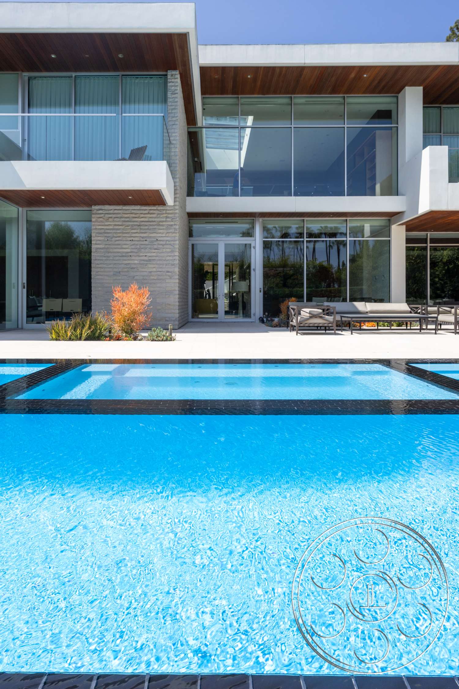 Modern 14 - natural light, exterior, modern architecture, minimalist style, glass walls, metal railing, rectangular swimming pool, floor-to-ceiling windows, stone feature wall, concrete patio floor, landscaped outdoor area, wood soffit ceiling, framed views of garden