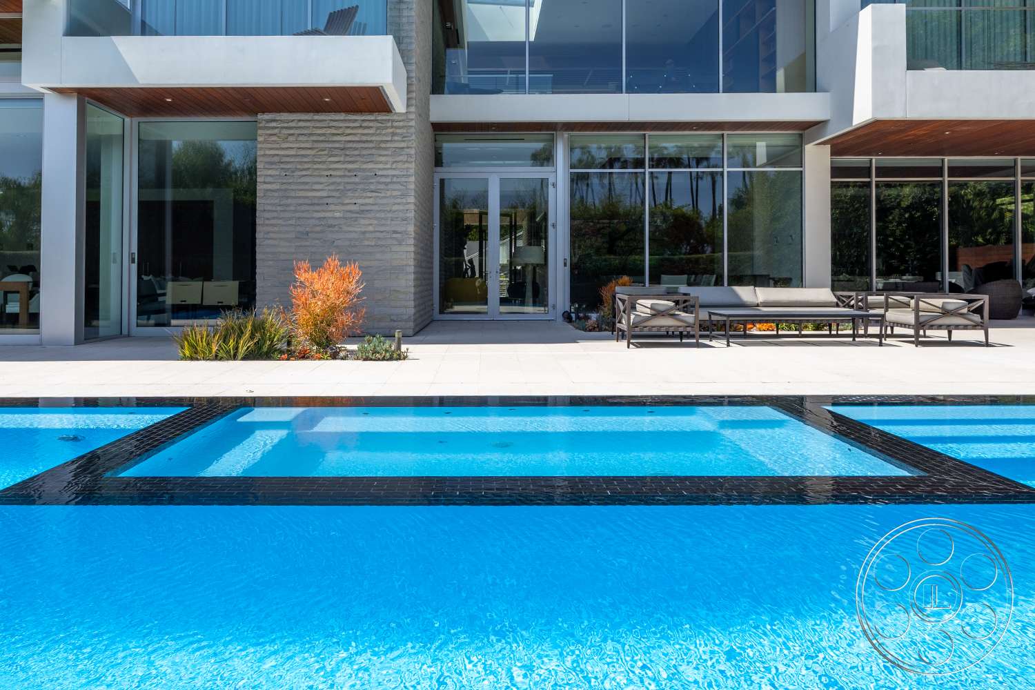 Modern 14 - exterior, glass sliding doors, outdoor seating area, rectangular swimming pool, modern architectural style, stone feature wall, blue water pool, landscaped garden area, concrete patio flooring, steel patio furniture, wood overhangs