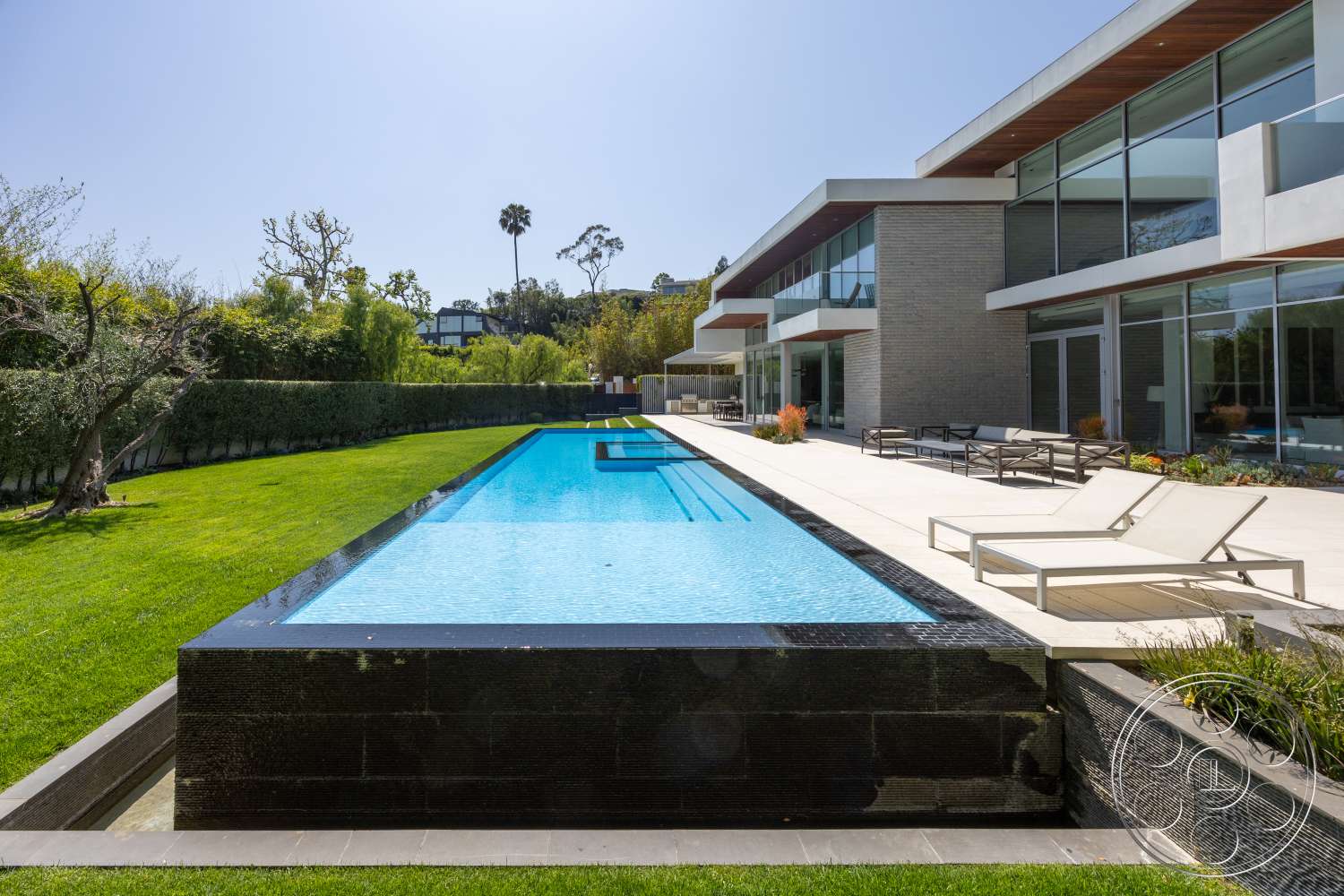 Modern 14 - exterior, landscaped garden, modern architecture, glass sliding doors, infinity pool, large floor-to-ceiling windows, textured stone walls, wooden patio furniture, stone pool deck, flat roof design, natural grass lawn, concrete pool border, concrete patio floor, rectangular patio