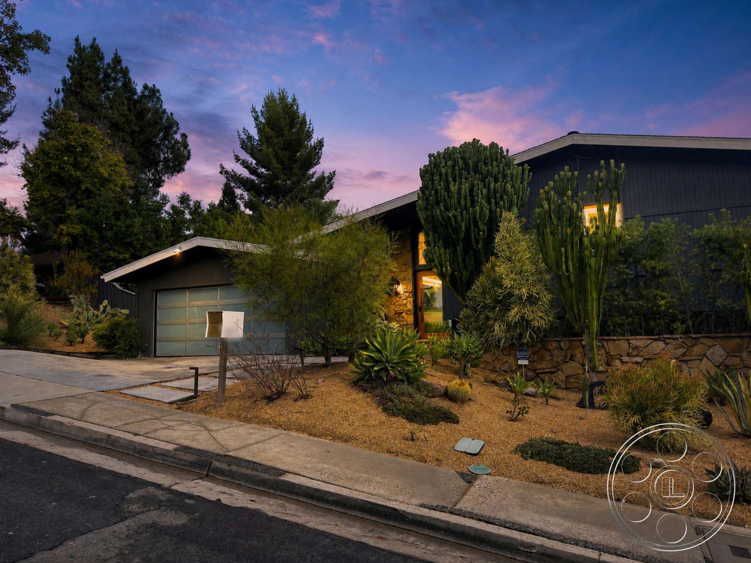 Americana 435 - exterior, modern architectural style, concrete driveway, desert landscaping, tropical palm trees, outdoor lighting fixtures, oversized windows, gravel ground cover, stone feature wall, flat roof design, urban hillside location, decorative stone border, wood panel siding, succulent garden plants, modern mailbox, angled geometric shapes