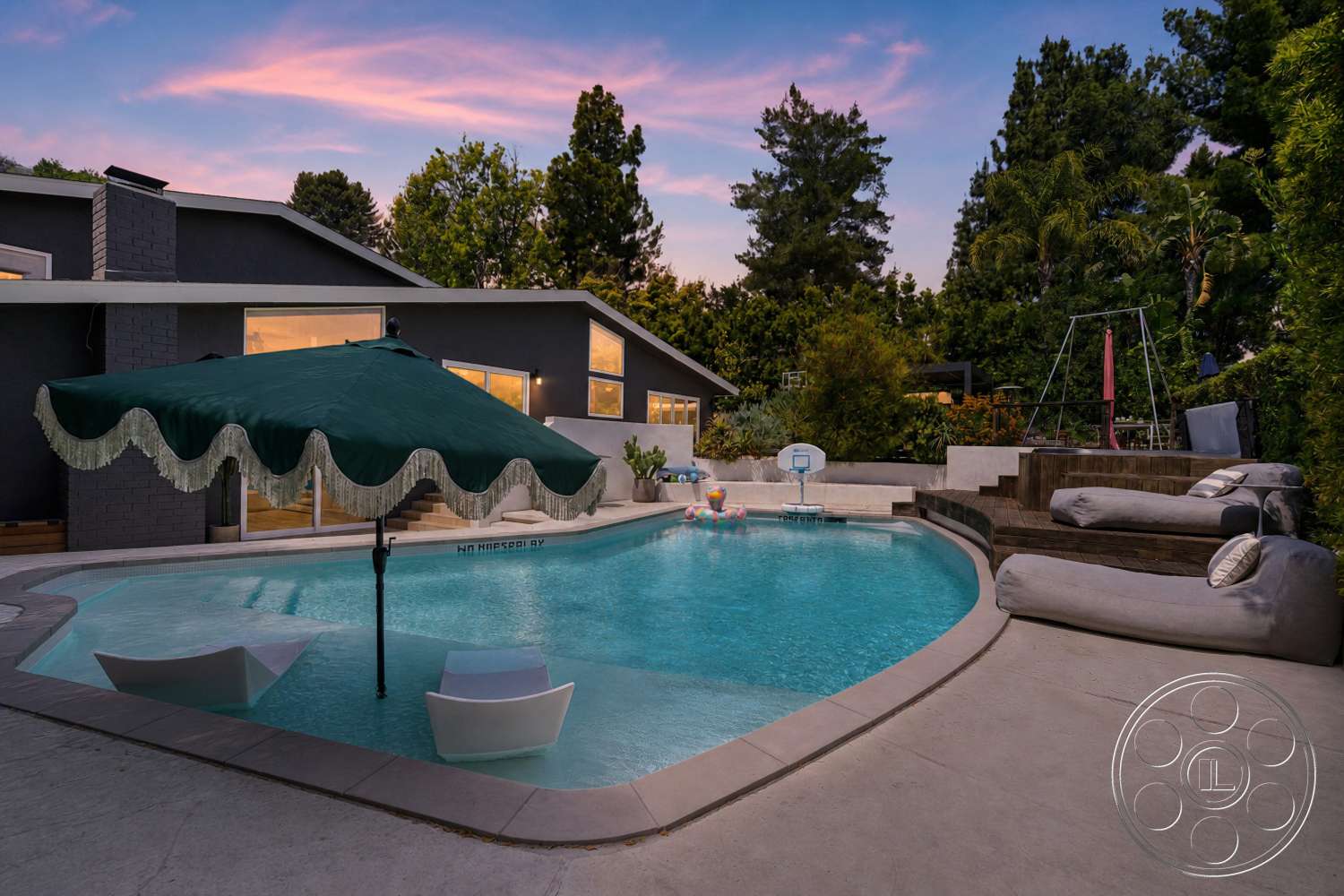 Americana 435 - landscaped garden, modern outdoor furniture, floor-to-ceiling windows, exposed brick wall, vaulted ceiling, evening lighting, rectangular pool, slate stone steps, concrete patio flooring, concrete pool border, urban backyard setting, green fabric umbrella, wooden deck seating area