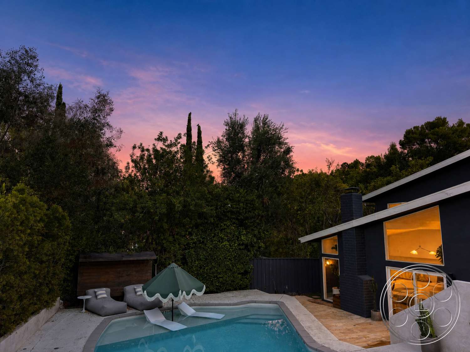 Americana 435 - landscaped garden, rectangular swimming pool, floor-to-ceiling windows, modern architectural style, concrete pool deck, wooden privacy fence, dark wood siding, green awning, brick chimney