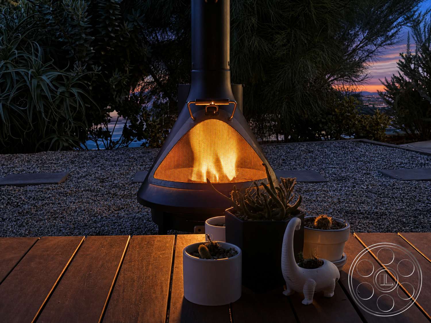 Americana 435 - exterior, outdoor living space, sunset view, gravel landscaping, wood deck flooring, metal outdoor fireplace, succulent plants in ceramic pots