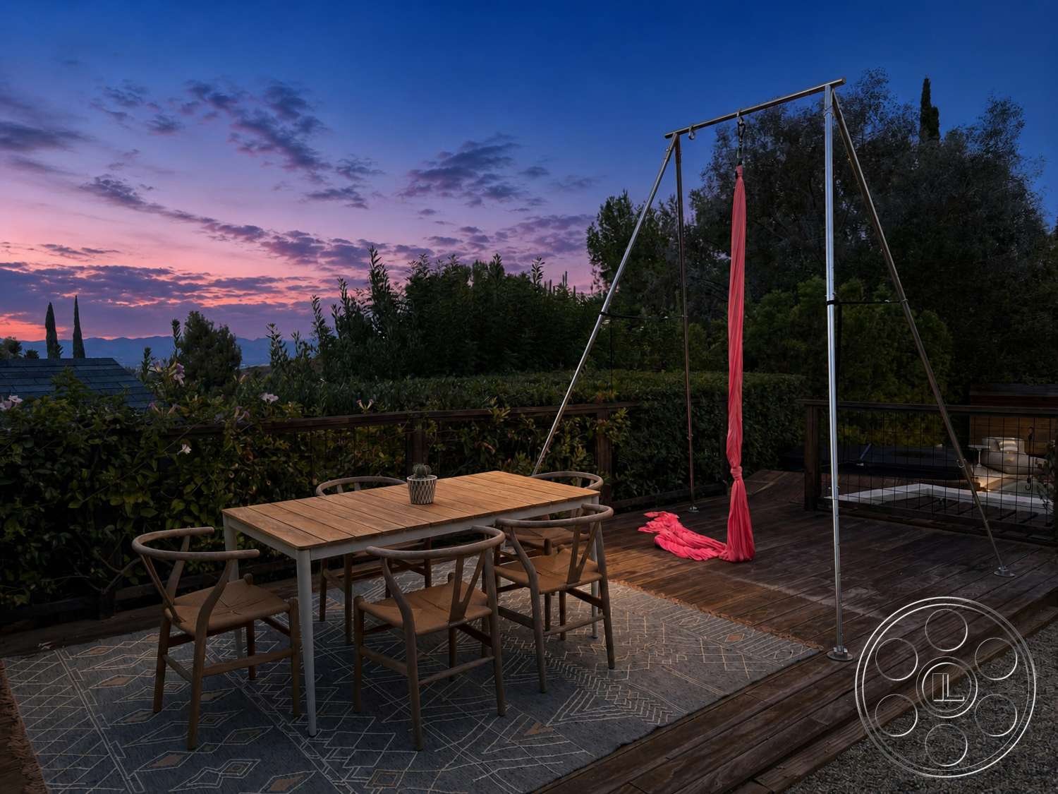 Americana 435 - exterior, landscaped garden view, sunset sky, wooden deck flooring, rectangular outdoor dining table, woven outdoor dining chairs, potted decorative plant, dark wood fence, metal swing frame, textured outdoor area rug, silk aerial hammock