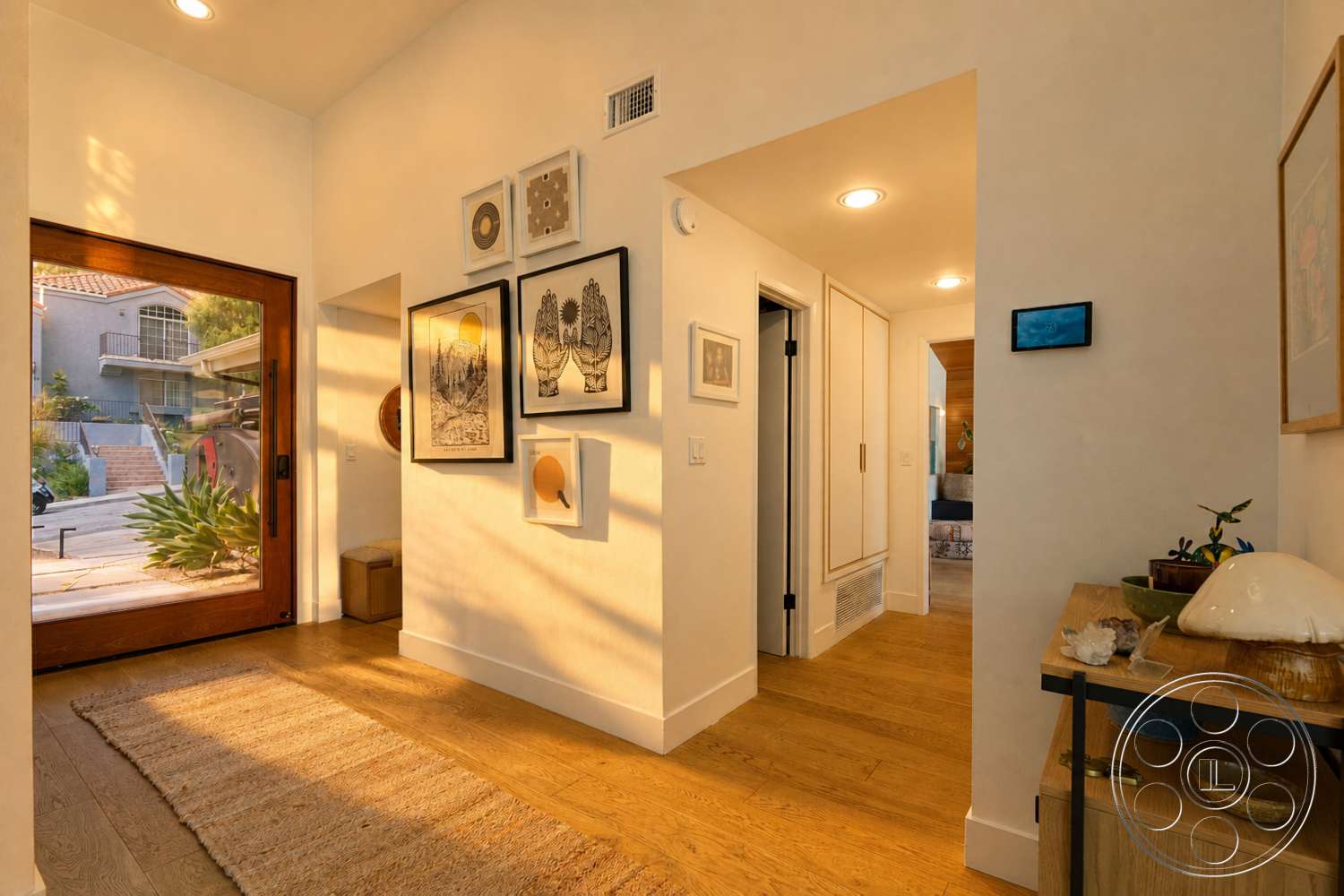 Americana 435 - area rug, framed wall art, textured plaster walls, wood front door, recessed ceiling lights, open hallway design, light oak hardwood flooring, flat-panel wall cabinetry