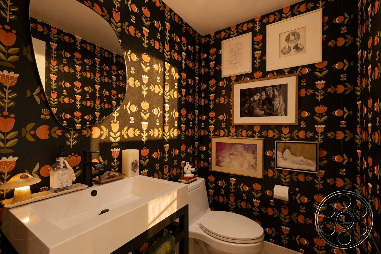 Americana 435 - black faucet, ambient lighting, framed artwork, floral wallpaper, black countertop, textured wall surfaces, oval mirror, decorative shelf, wall-mounted toilet, black wallpaper with floral design, white bathroom sink, wall art frames