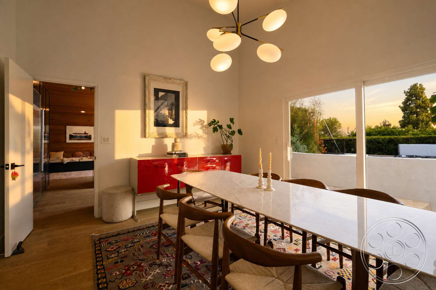 Americana 435 - indoor plant, textured area rug, glass sliding doors, framed artwork, floor-to-ceiling windows, vaulted ceiling, sunset view, decorative light fixture, marble dining table, white painted walls, hardwood dining room floors, mid-century modern dining chairs, red lacquered sideboard