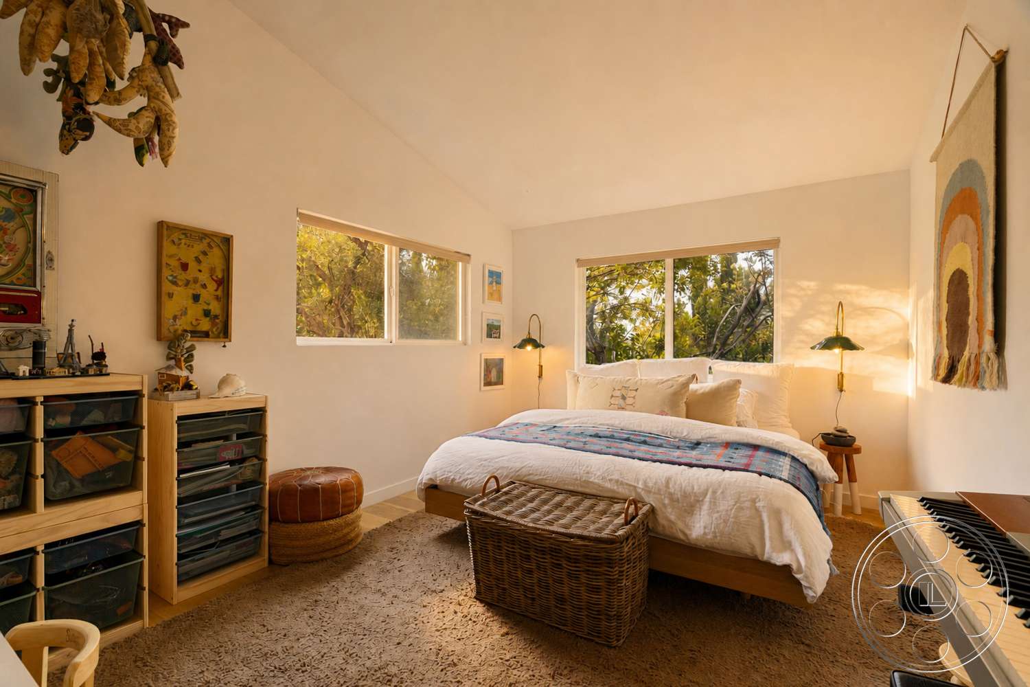 Americana 435 - hardwood flooring, woven basket, green plants, glass windows, wooden bed frame, woven area rug, king-sized bed, decorative throw pillows, minimalist bedside lamps, vaulted bedroom ceiling, wooden storage drawers, light-colored plaster walls, textile wall art, round leather ottoman