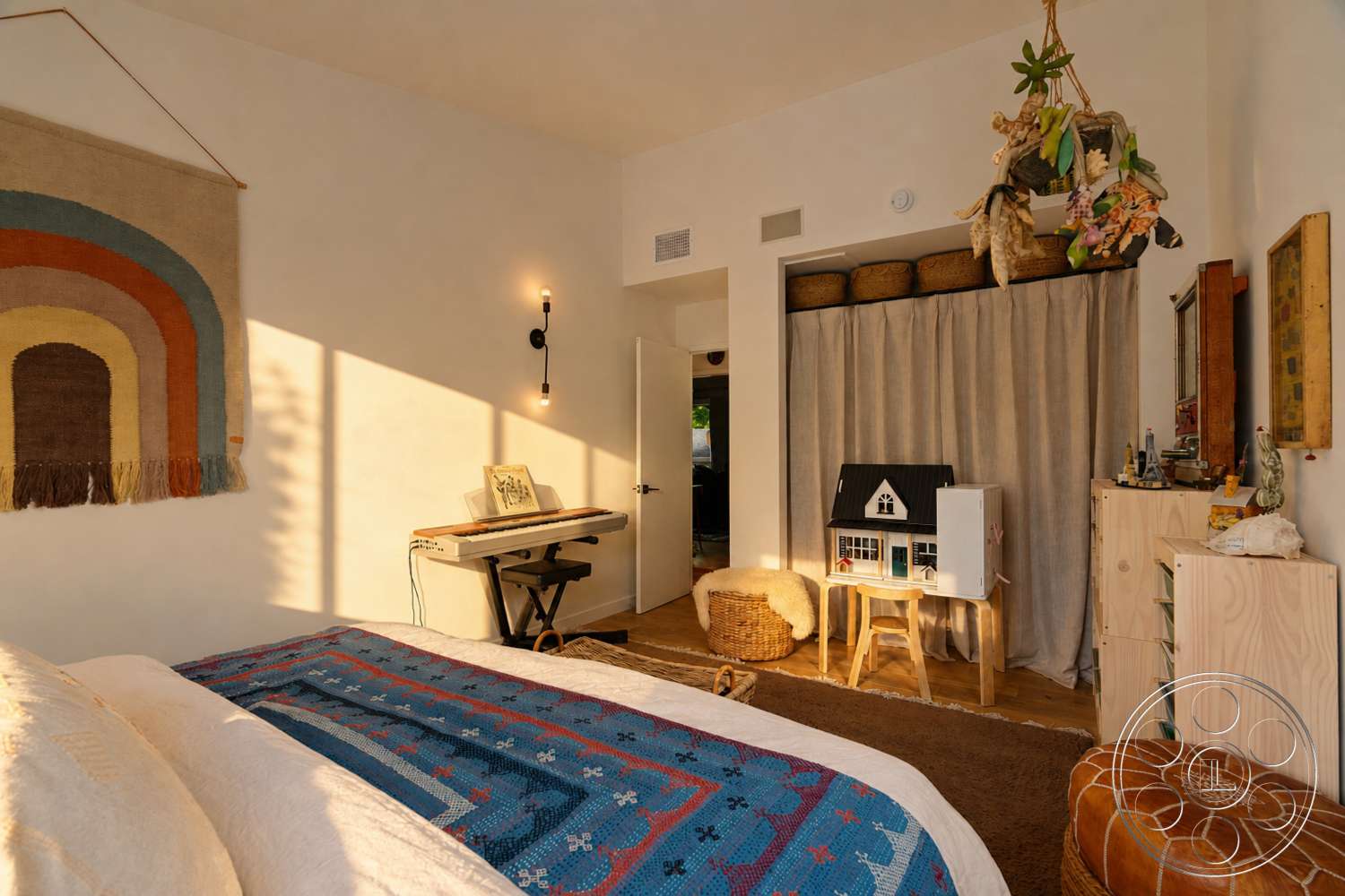 Americana 435 - modern light fixtures, textured plaster walls, woven wall hanging, baskets for storage, natural fiber area rug, hardwood bedroom floors, curtained closet, decorative table with miniature house, potted hanging plants, functional workspace with keyboard
