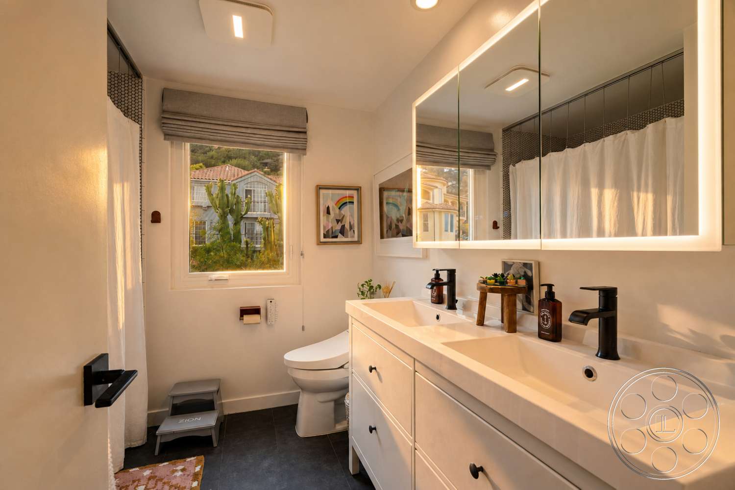 Americana 435 - indoor plants, contemporary styling, black tile flooring, interior bathroom, white painted walls, modern faucet fixtures, decorative artwork on walls, floating vanity with drawers, double sink countertop, framed mirror with LED lighting, roller shades window treatment, bathroom storage solutions, shower curtain partition