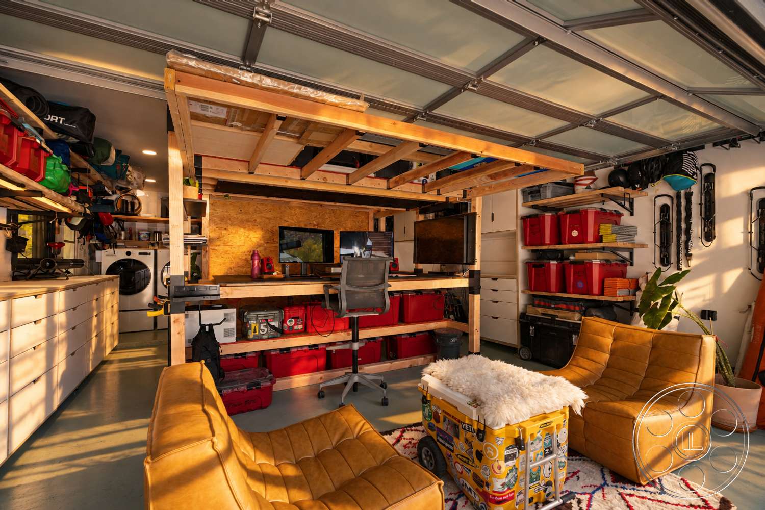 Americana 435 - textured accent wall, exposed wooden ceiling beams, industrial-style lighting, multi-functional workspace, contemporary office chair, wood framed desk structure, softwood shelving units, colored plastic storage bins, gray epoxy garage floor, beige leather armchairs, white laundry machine, wall-mounted storage racks, computer monitor workstation, brightly lit garage environment