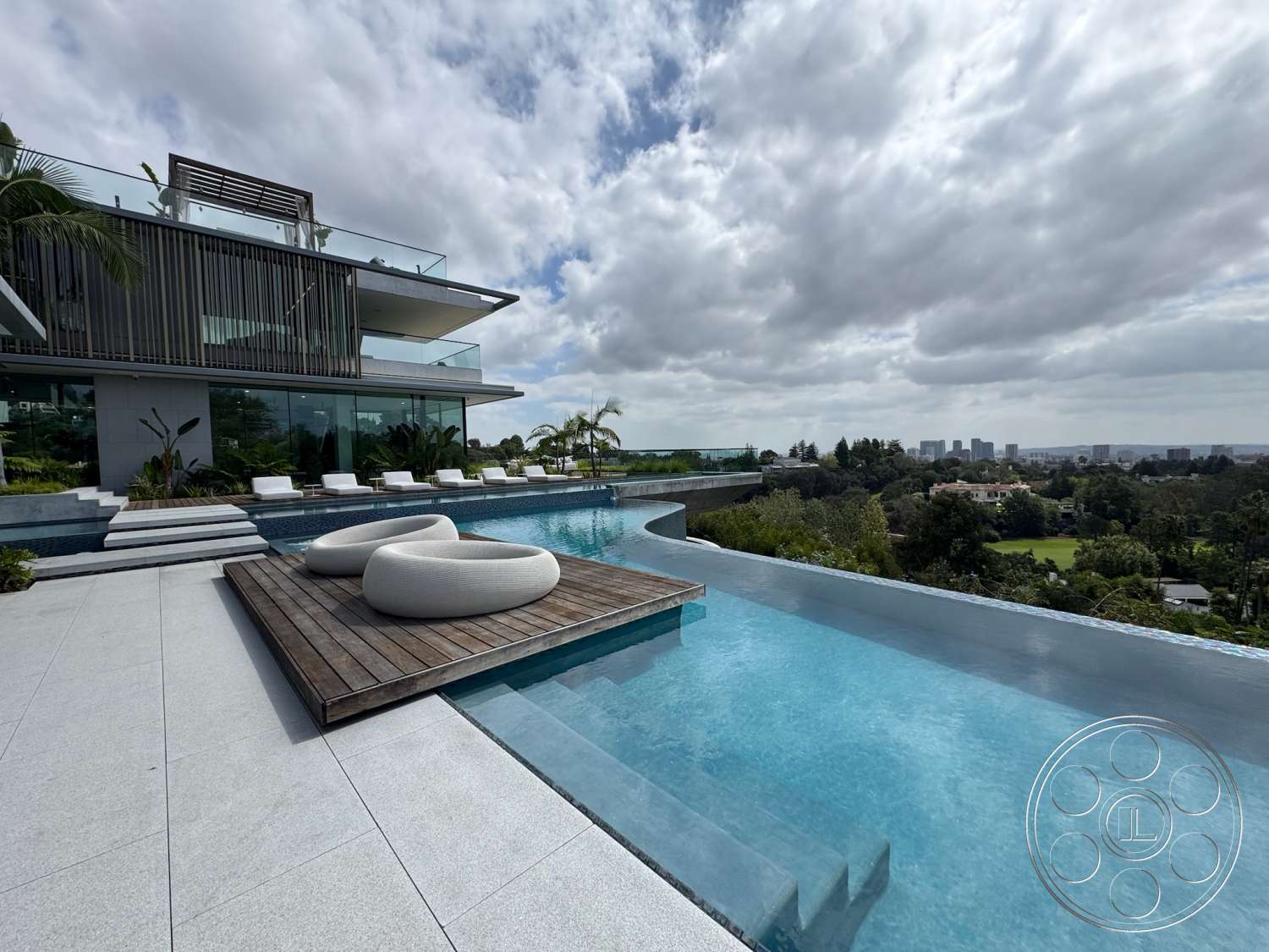 The Bellagio Estate - exterior, glass railing, infinity pool, stone pool deck, concrete patio flooring, wood deck lounge area