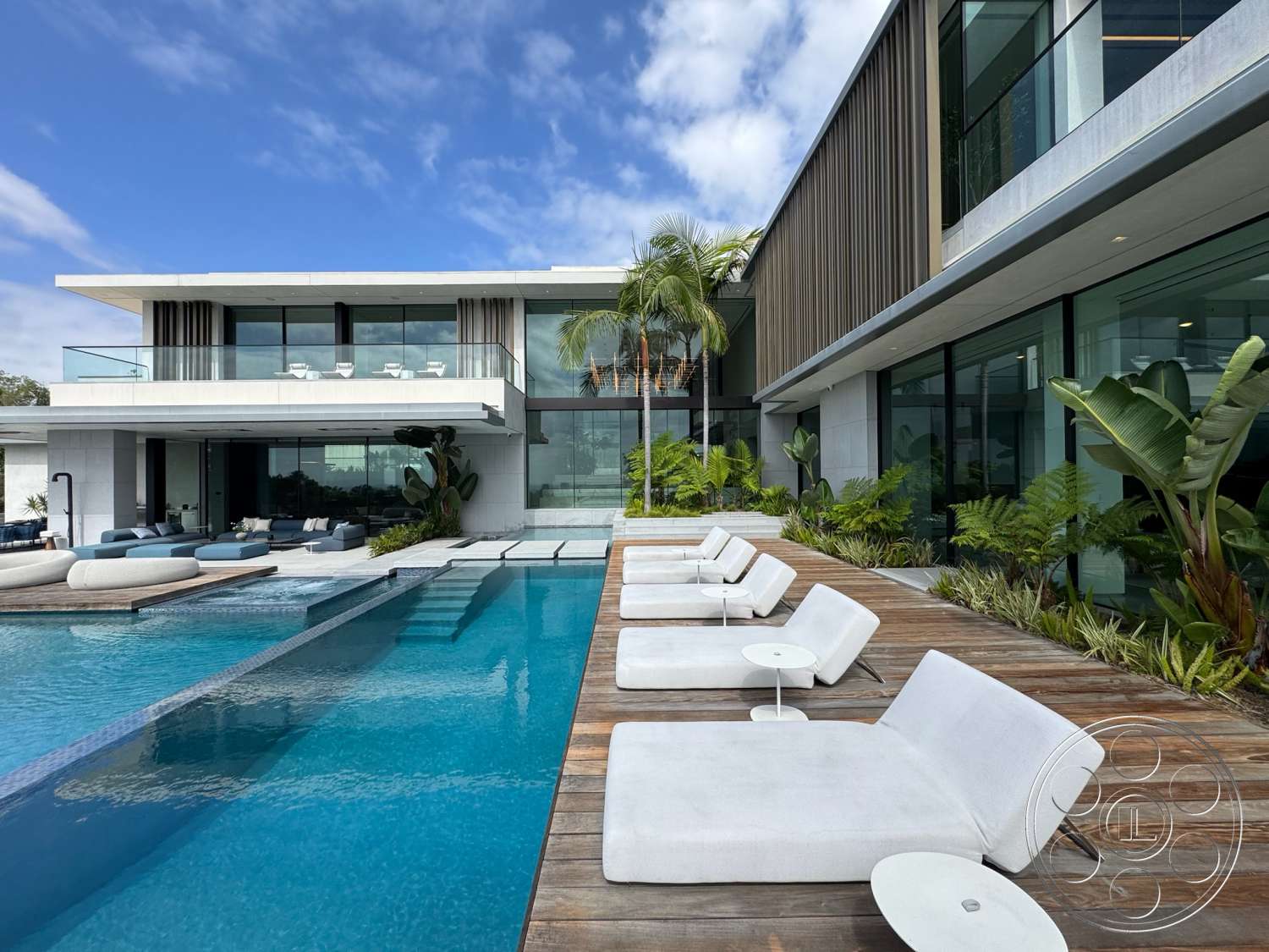 The Bellagio Estate - exterior, modern architecture, glass railing, floor-to-ceiling windows, planted greenery, tropical landscaping, infinity pool, concrete pool deck, rectangular pool, horizontal wood siding, stucco wall finish, concrete exterior walls, wooden deck patio