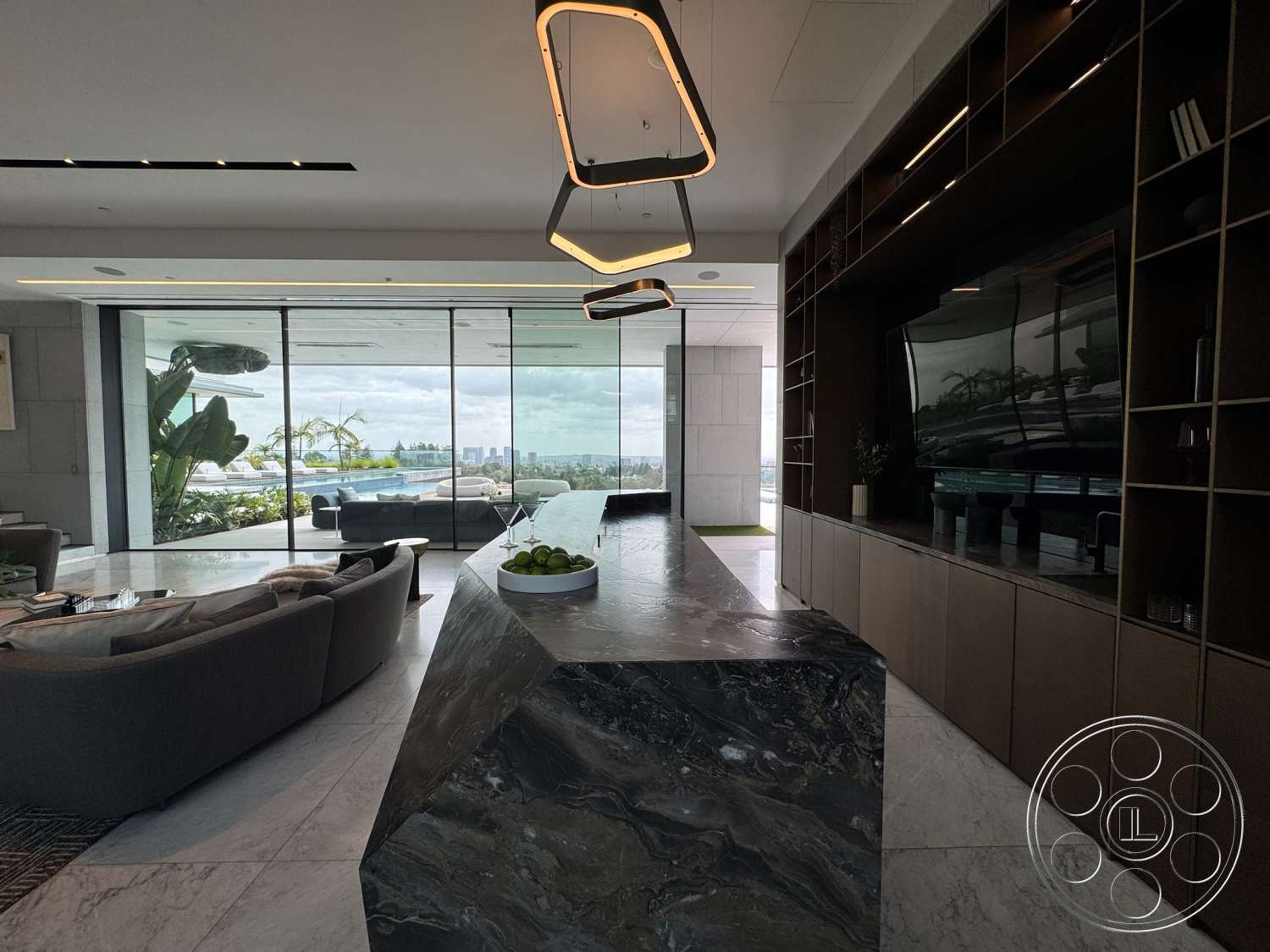 The Bellagio Estate - neutral color palette, open floor plan, minimalist design elements, glass sliding doors, floor-to-ceiling windows, modern architectural style, marble flooring, linear pendant lighting, dark stone countertop, marble kitchen island, panoramic city skyline view, contemporary cabinetry, luxury living room seating, stylish decorative plants