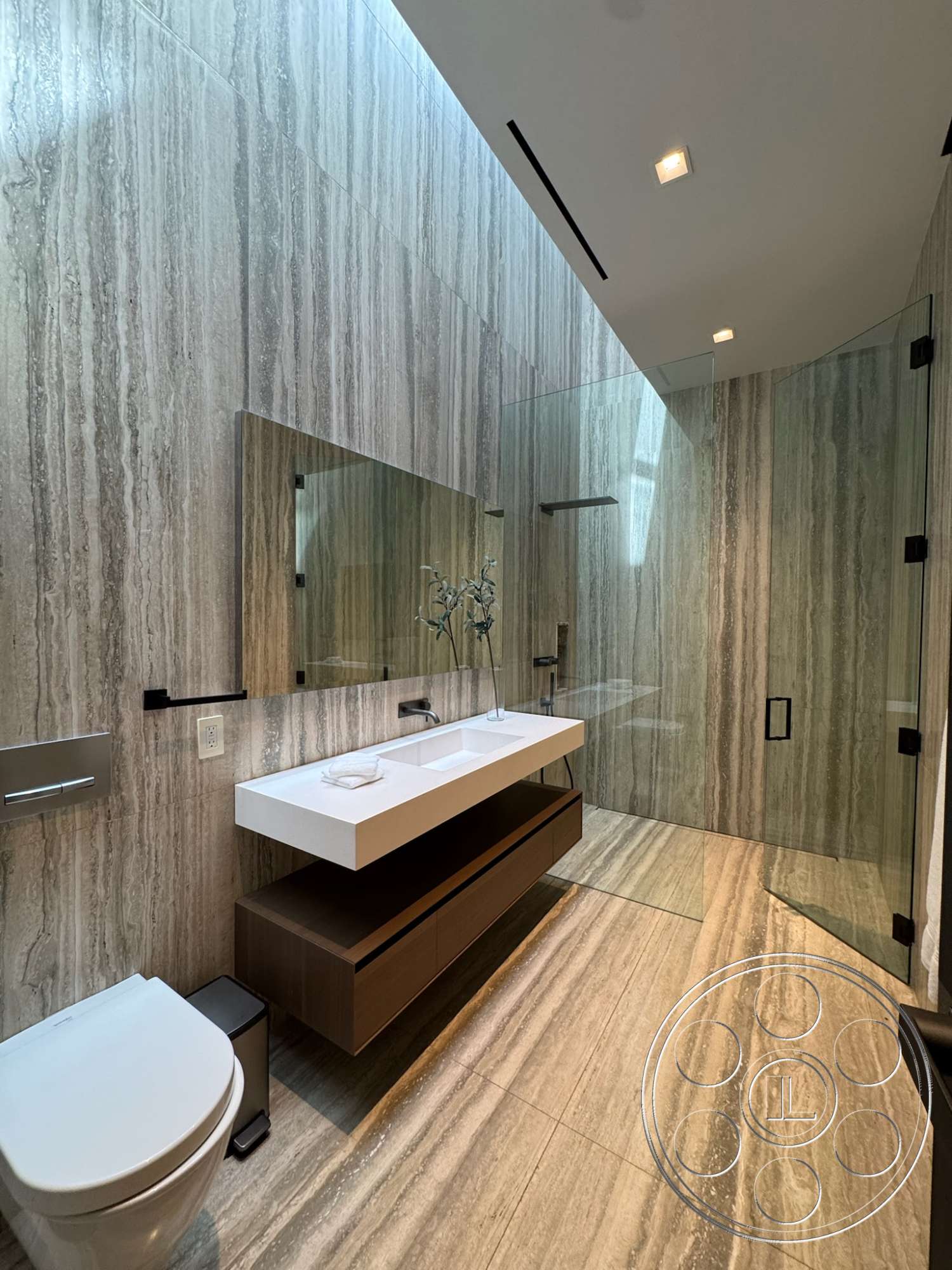 The Bellagio Estate - dark wood cabinetry, glass shower enclosure, modern bathroom lighting, tile bathroom walls, marble bathroom flooring, floating bathroom vanity, wall-mounted toilet, white quartz sink, linear ceiling light