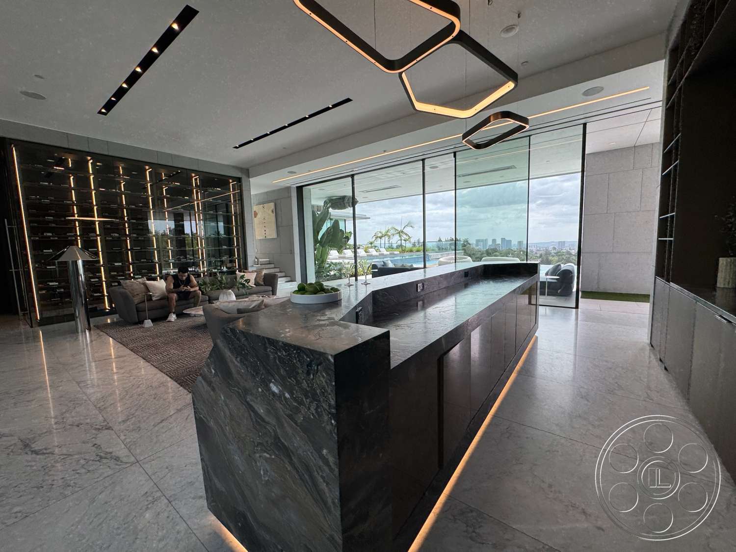The Bellagio Estate - high ceilings, minimalist decor, open concept layout, glass sliding doors, floor-to-ceiling windows, textured wall panels, city skyline view, marble flooring, linear pendant lighting, dark stone countertop, modern seating area, contemporary kitchen island, seamless glass partition, wine cellar feature wall