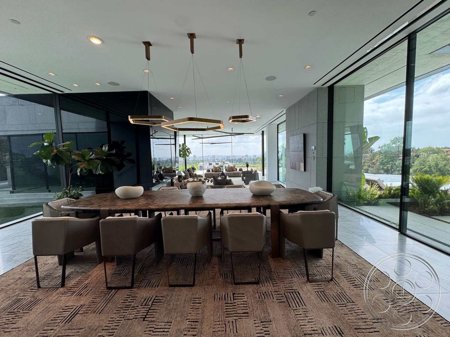The Bellagio Estate - contemporary design, textured area rug, open floor plan, upholstered dining chairs, large glass windows, wood dining table, panoramic view, modern dining room, stone feature wall, recessed ceiling lights, potted indoor plants, geometric pendant lights, marble floor tiles