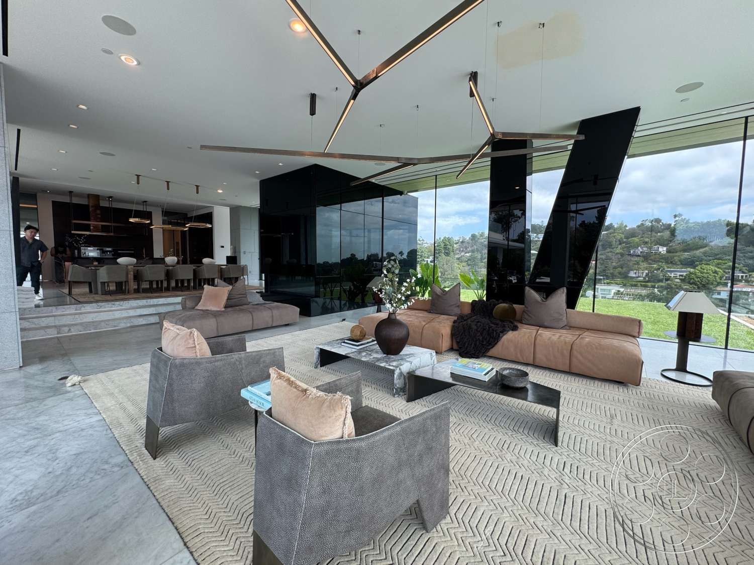 The Bellagio Estate - neutral color palette, contemporary design, indoor plants, open floor plan, concrete flooring, upholstered dining chairs, textured wall accents, sliding glass doors, floor-to-ceiling windows, minimalist coffee table, dark wood dining table, recessed ceiling lights, upholstered sectional sofa, glass wall panels, views of landscaped garden, vaulted ceilings, modern linear pendant lights, herringbone area rug