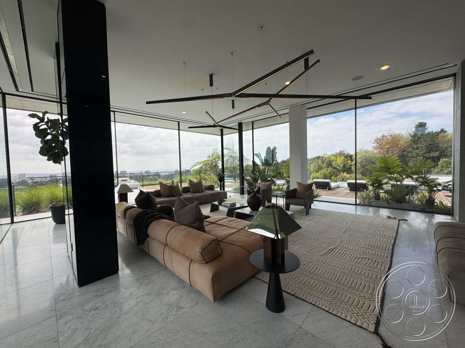 The Bellagio Estate - neutral color palette, minimalist design, textured area rug, open floor plan, plush sectional sofa, floor-to-ceiling windows, outdoor view, marble flooring, contemporary living room, light-filled space, dark wood accent table, modern architectural details, greenery with potted plants, linear chandelier