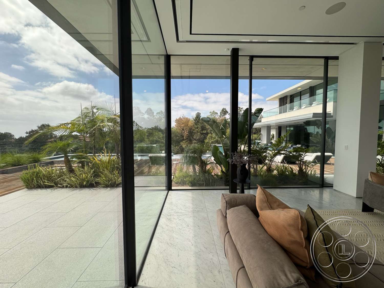 The Bellagio Estate - minimalist decor, indoor plants, contemporary furniture, open floor plan, glass coffee table, sliding glass doors, floor-to-ceiling windows, exposed ceiling, marble flooring, lush garden view, outdoor pool area, modern sectional sofa, wood deck patio, steel balcony railing