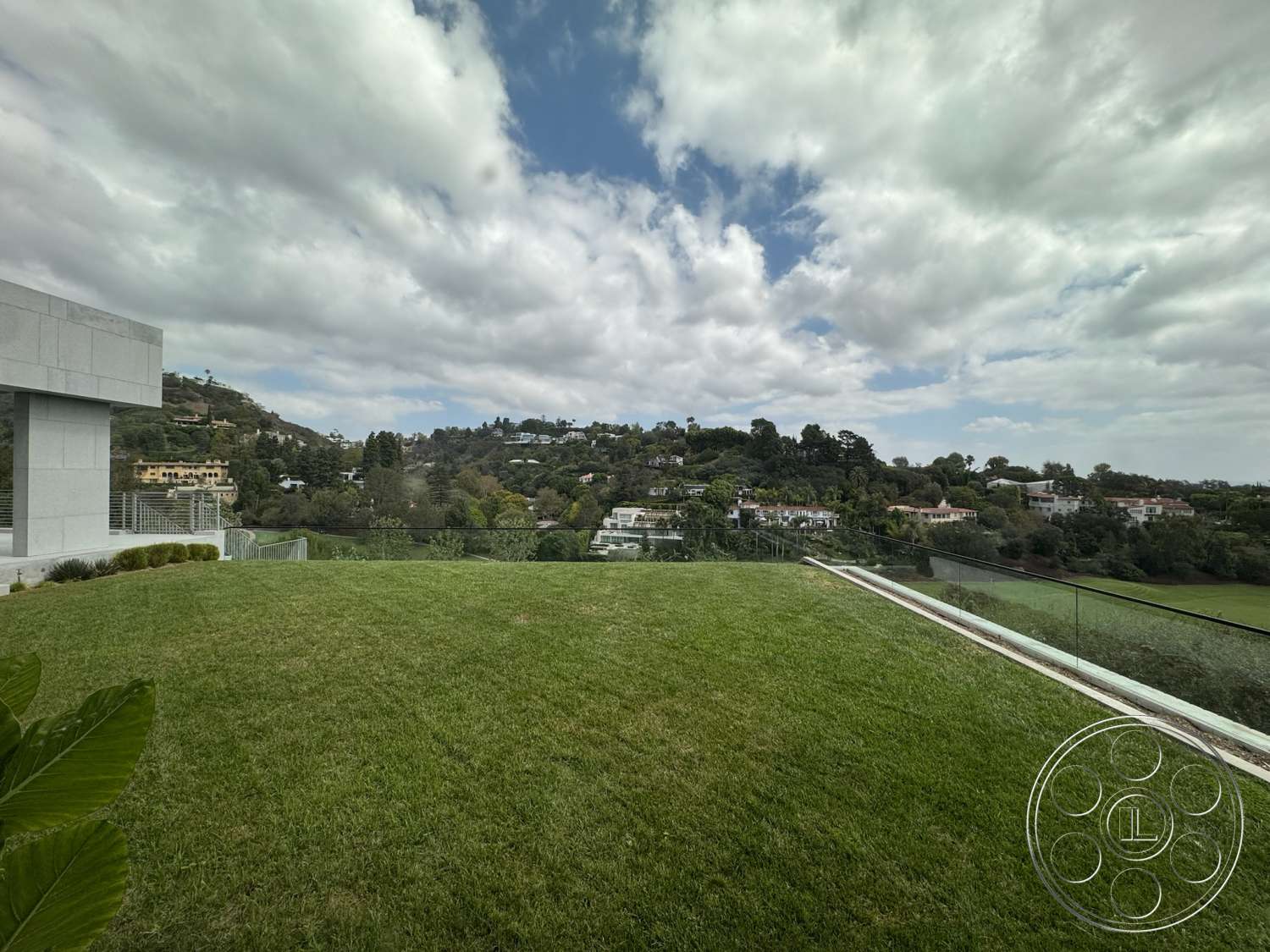 The Bellagio Estate - exterior, glass railing, lush green lawn, modern architectural style, city skyline view, hillside location, concrete patio floor