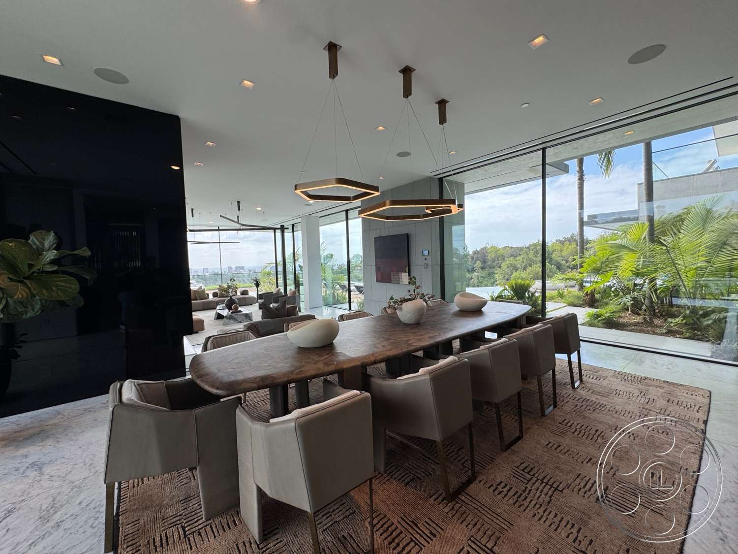 The Bellagio Estate - neutral color palette, contemporary design, textured area rug, open floor plan, modern pendant lighting, upholstered dining chairs, wood dining table, floor-to-ceiling windows, urban view, lush indoor plants, glass wall panels, marble floor tile, luxurious dining space