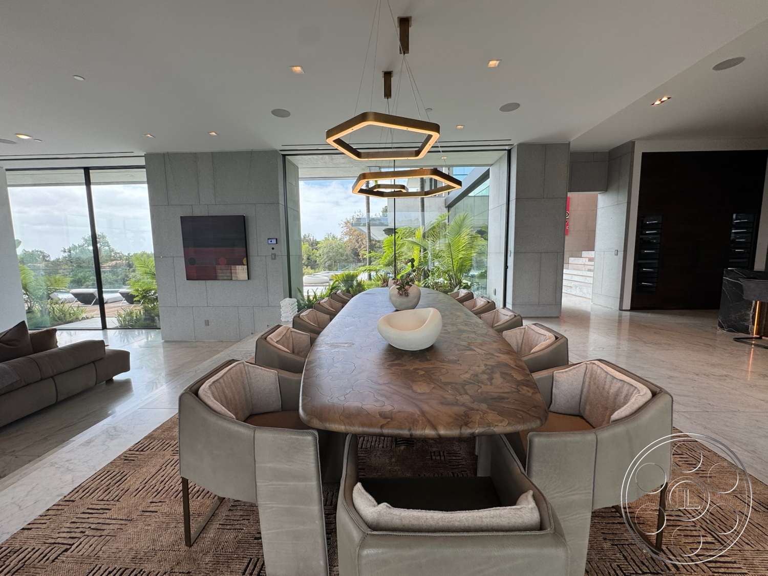 The Bellagio Estate - stone accent wall, textured area rug, upholstered dining chairs, large glass windows, marble flooring, modern sectional sofa, potted indoor plants, glass wall partition, rectangular dining table with wooden surface, pendant lighting with geometric design, minimalist wall artwork