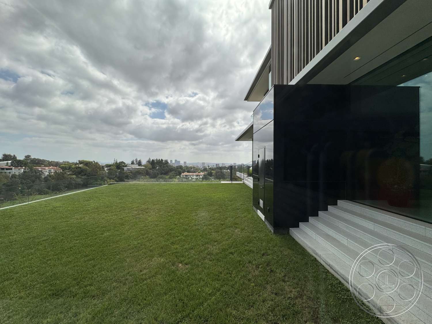 The Bellagio Estate - exterior, glass railing, modern architectural style, city skyline view, hillside location, landscape grass lawn, concrete patio steps, wood slat facade