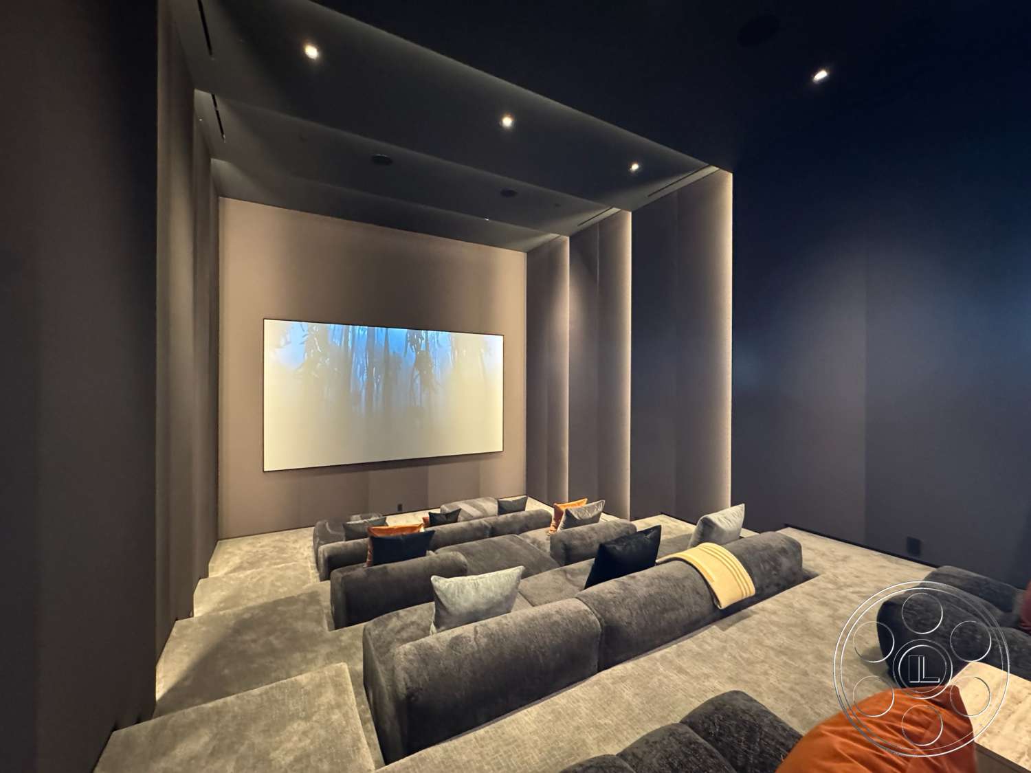 The Bellagio Estate - recessed ceiling lights, low-profile furniture, acoustic panel walls, projector screen wall, home theater room, dark gray carpet flooring, plush sectional seating, modern design details, floating ceiling design