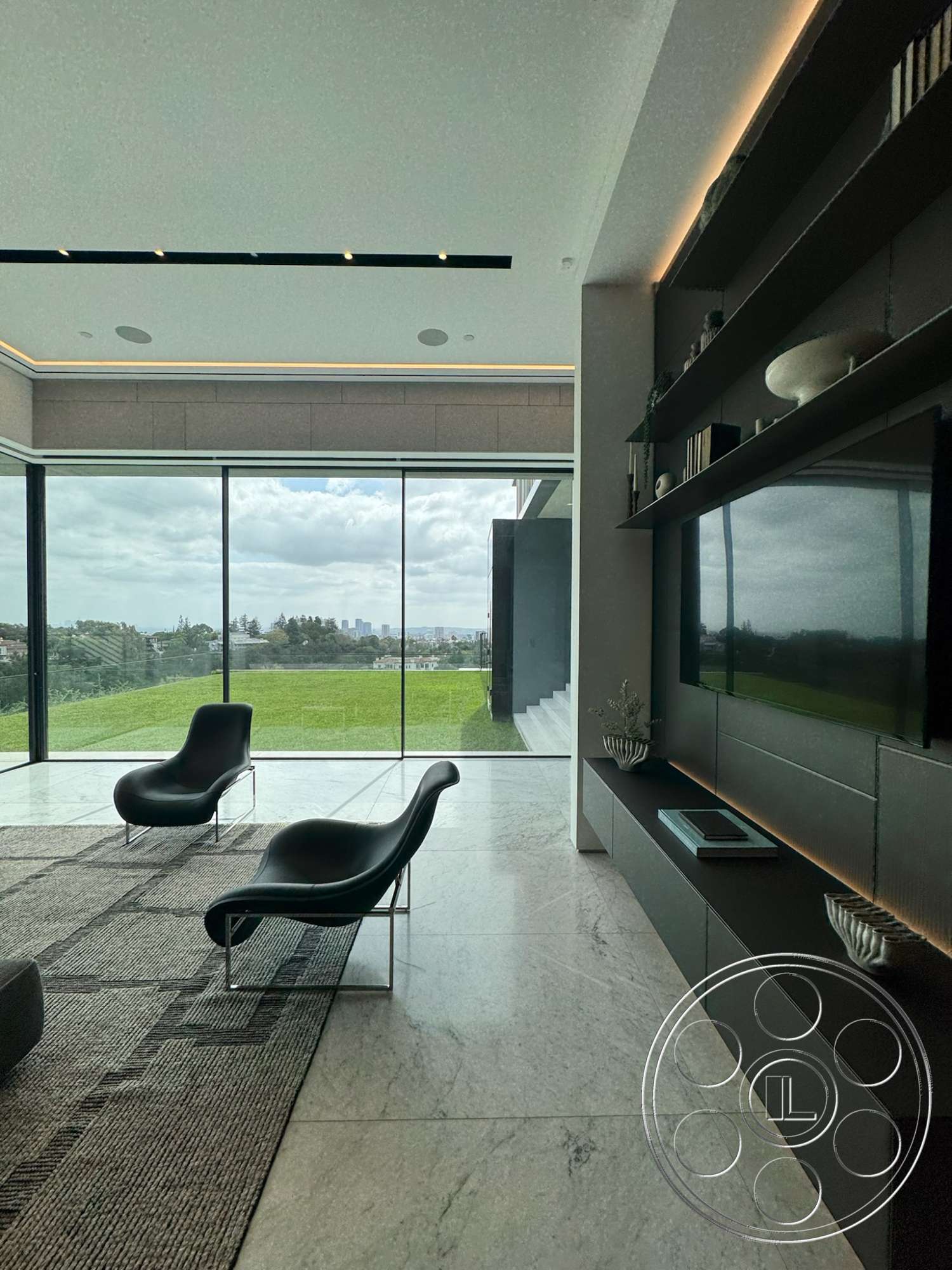 The Bellagio Estate - neutral color palette, contemporary style, minimalist design, textured area rug, open floor plan, floor-to-ceiling windows, marble flooring, indirect LED lighting, black leather lounge chairs, modern wall-mounted shelving, panoramic view of green landscape