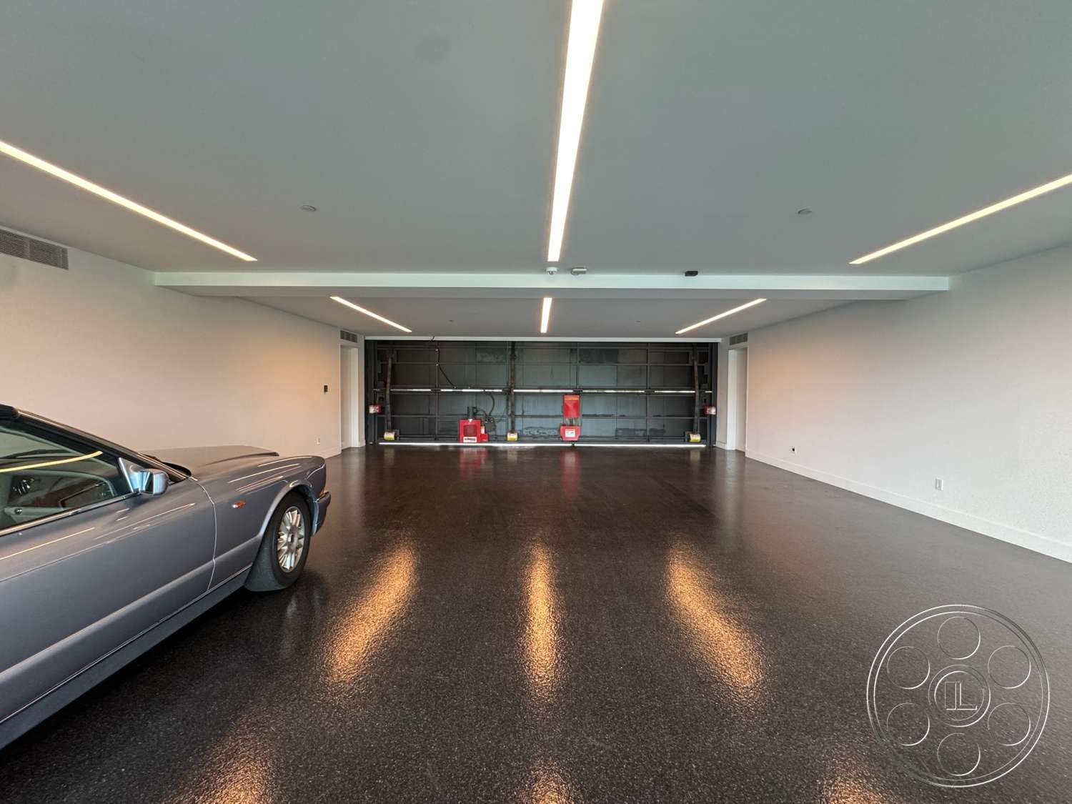 The Bellagio Estate - minimalist design, open space layout, smooth white walls, interior garage space, polished concrete garage floor, steel garage door, modern ceiling with linear LED lighting, highly organized storage system