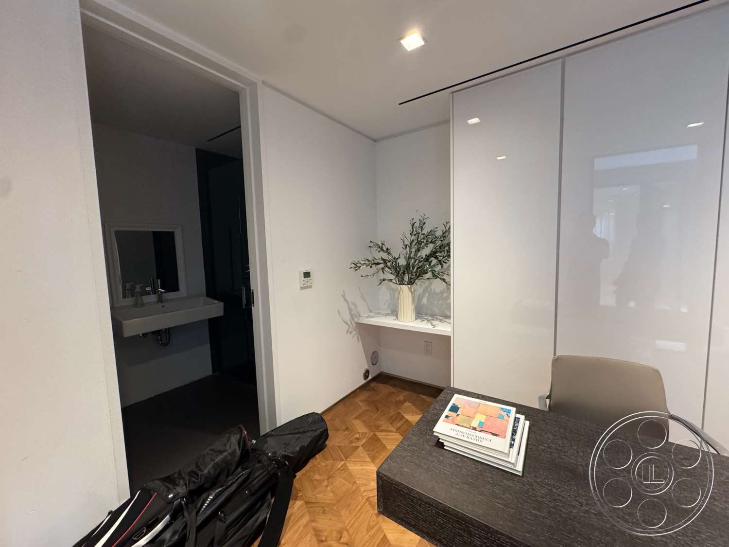 The Bellagio Estate - minimalist design, built-in cabinetry, contemporary light fixtures, white painted walls, glass door entrance, parquet wood flooring, modern office desk, corner plant decoration, elegant vase arrangement