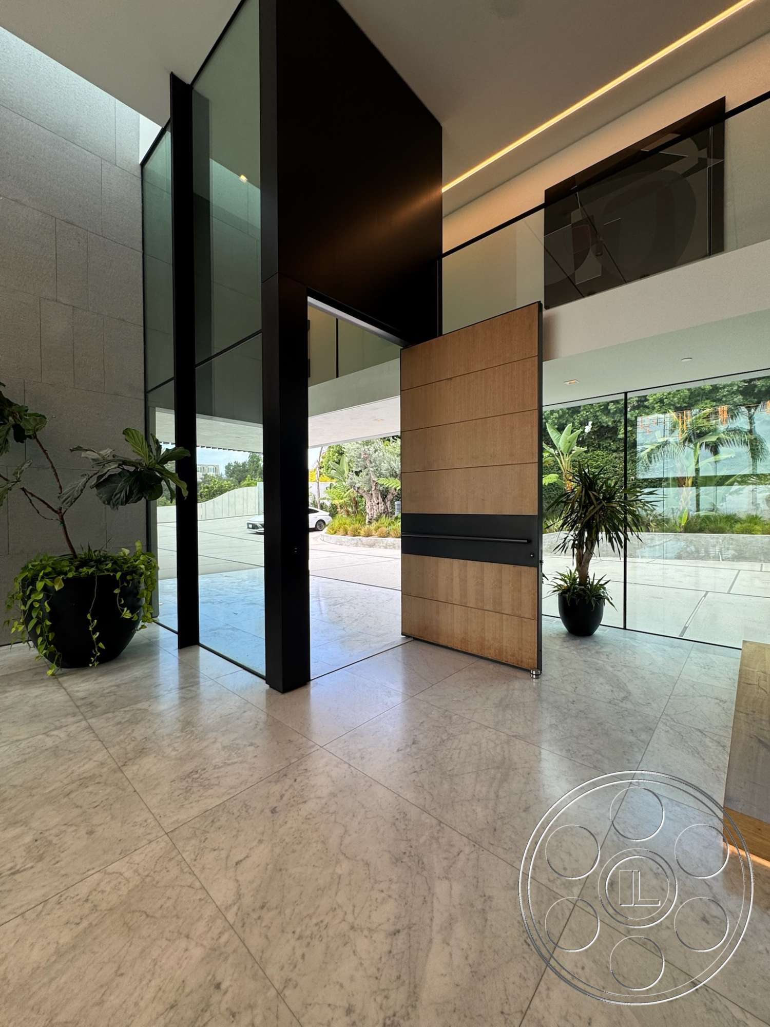 The Bellagio Estate - open concept layout, large glass windows, geometric shapes, marble flooring, indoor plant decor, contemporary architectural style, smooth ceiling with recessed lighting, black vertical accent wall, wooden pivot door