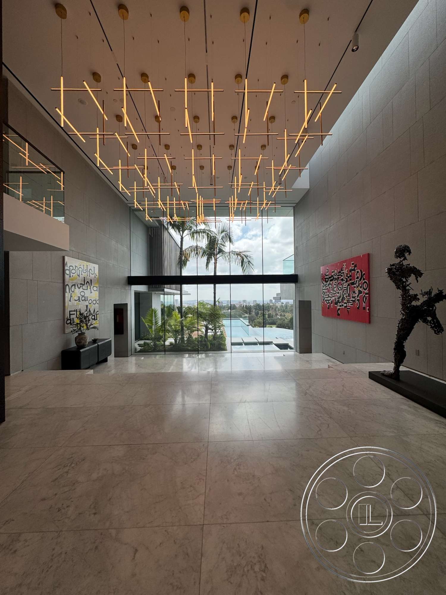 The Bellagio Estate - minimalist aesthetic, open concept design, textured concrete walls, marble flooring, modern light fixture, palm tree view, floor-to-ceiling glass walls, contemporary art wall, luxury entrance