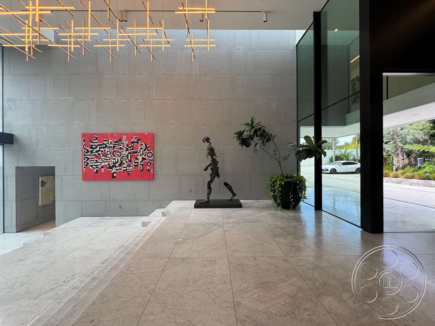 The Bellagio Estate - open concept layout, marble flooring, large potted plants, modern sculpture, floor-to-ceiling glass walls, exposed concrete accent wall, sliding glass door entry, minimalist design features, architectural lighting fixture, rectangular art piece