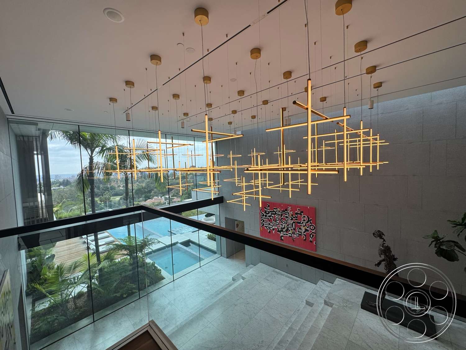 The Bellagio Estate - natural light, minimalist design, floor-to-ceiling windows, lush landscaping, marble flooring, luxury home, sculptural decor, open-concept layout, pendant lighting fixture, contemporary art wall, infinity pool view, architectural glass walls, modern staircase railing, dramatic ceiling height, suspended linear light design