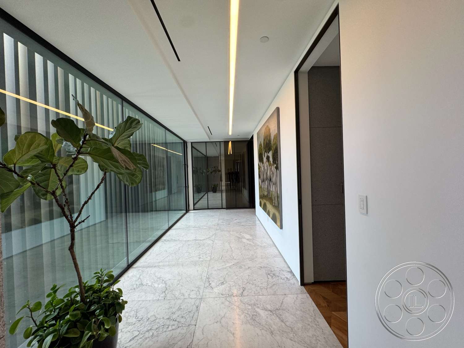 The Bellagio Estate - indoor plant decor, glass partition walls, wooden door frame, white painted walls, artwork wall display, vertical slat wall treatment, marble hallway flooring, recessed linear lighting