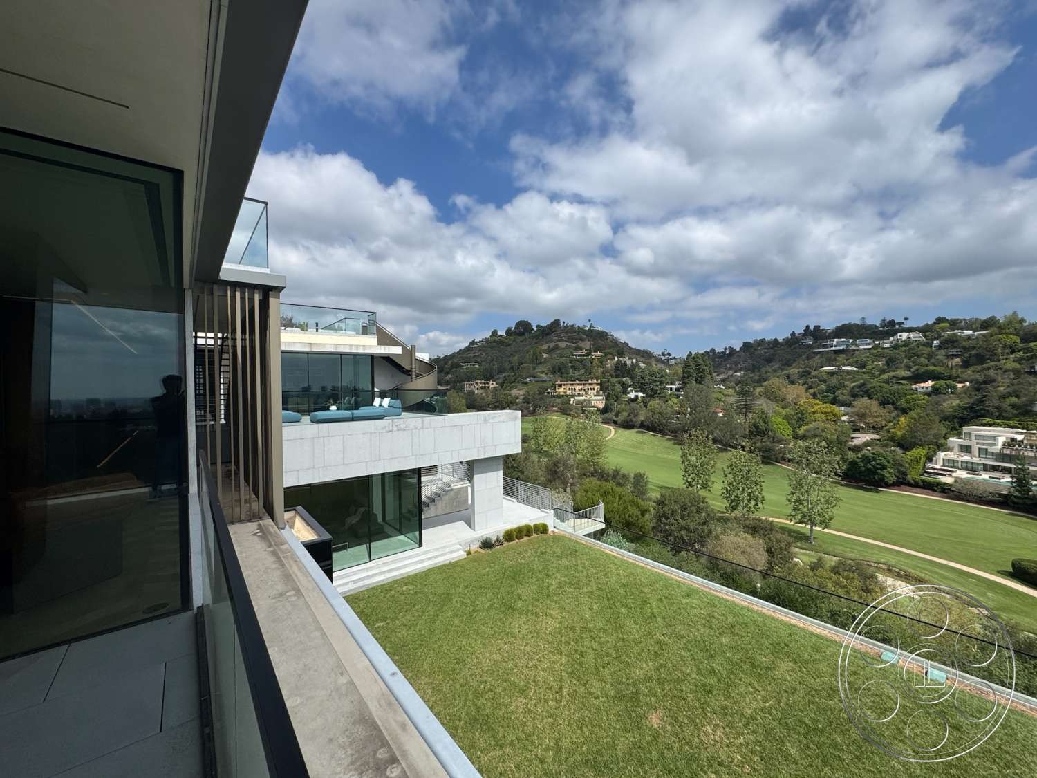 The Bellagio Estate - exterior, glass sliding doors, modern architectural style, mountain view setting, flat roof structure, concrete terrace flooring, horizontal wood slat railing, landscaped lawn area