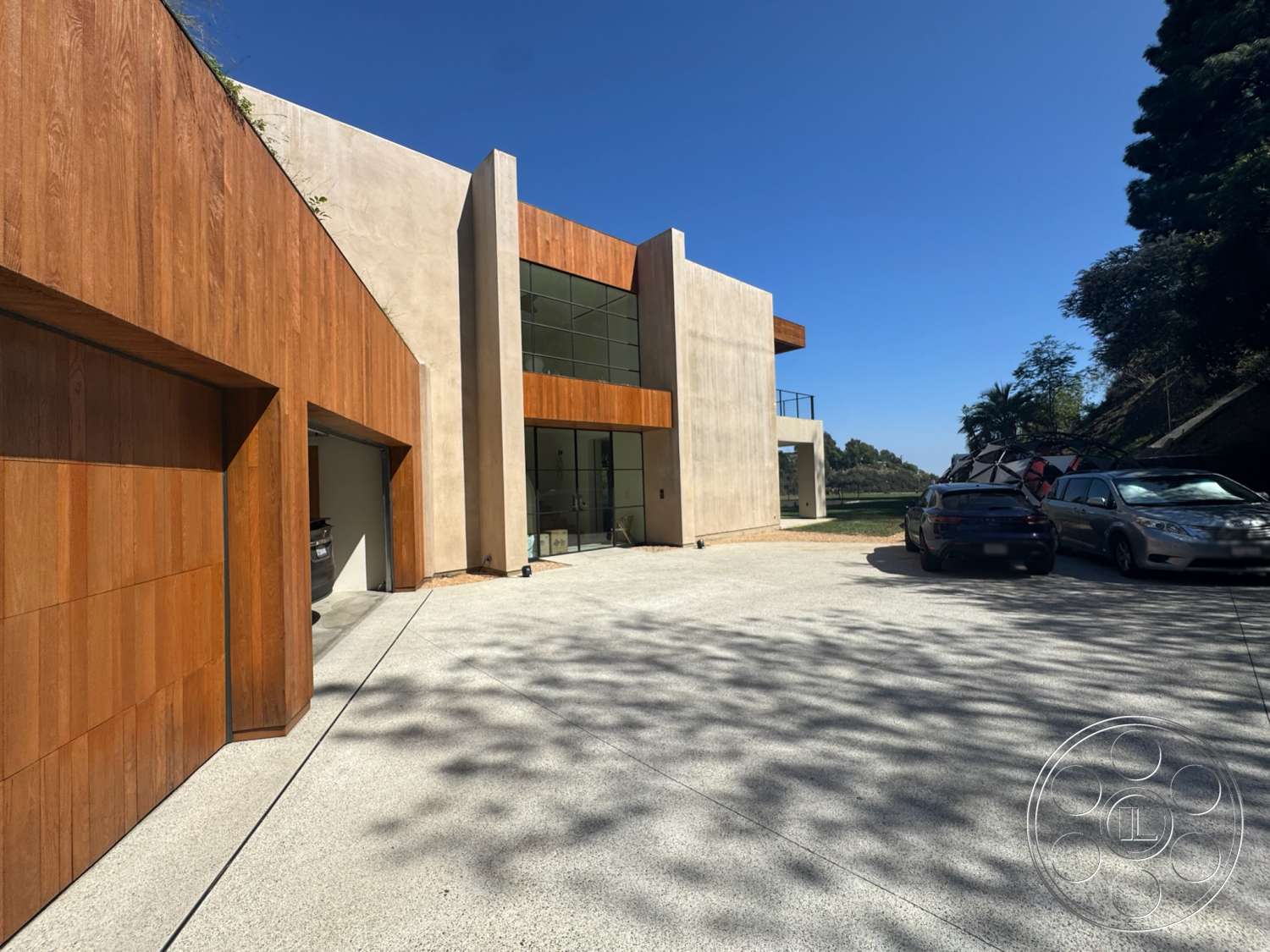 Modern 527 - exterior, floor-to-ceiling windows, modern architectural style, concrete driveway, textured plaster walls, wood accent features, rectangular house shape, wood panel garage door, landscaped surrounding area
