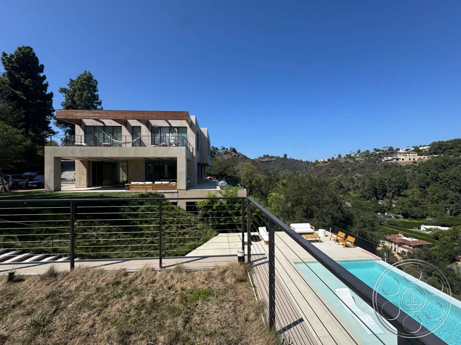 Modern 527 - large windows, exterior, flat roof, open floor plan, glass sliding doors, concrete walls, outdoor lounge area, modern architectural style, wood deck, stainless steel railings, landscaped hillside, infinity pool, rectangular pool, urban hillside view, metal railing detail
