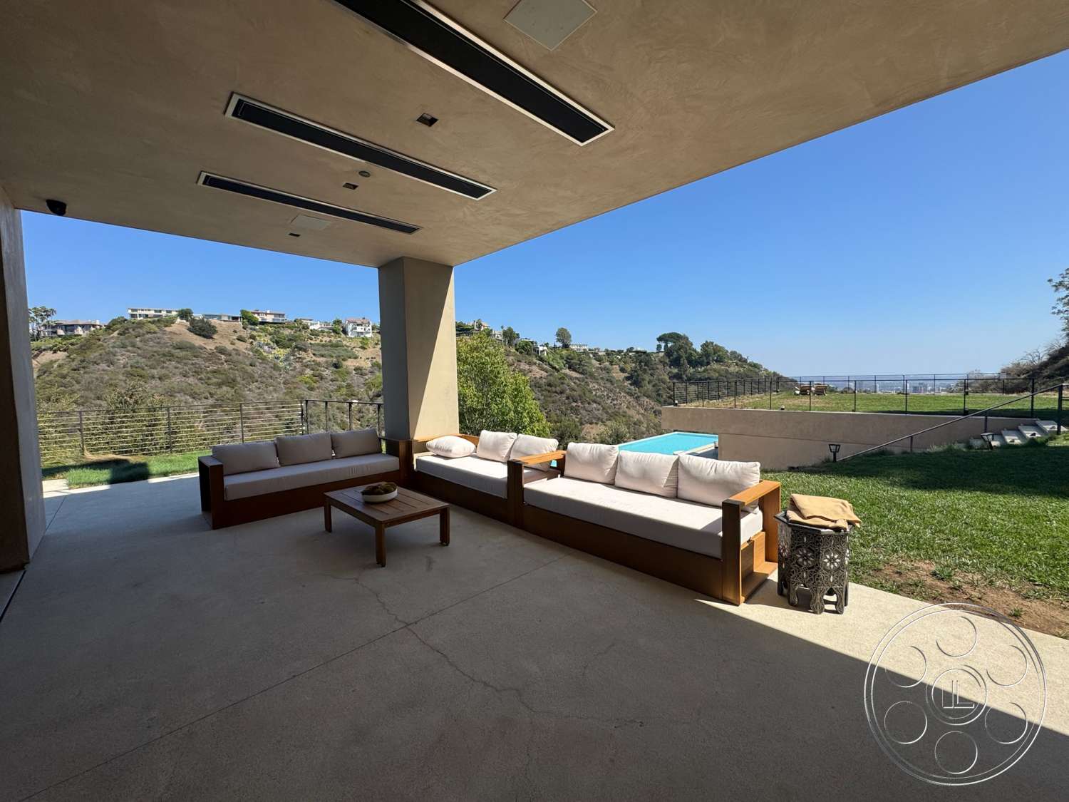 Modern 527 - exterior, minimalist design, wooden coffee table, glass railing, panoramic view, open outdoor space, rectangular pool, hillside location, stucco wall, modern outdoor seating area, concrete patio floor, luxury home setting, landscaped grass area