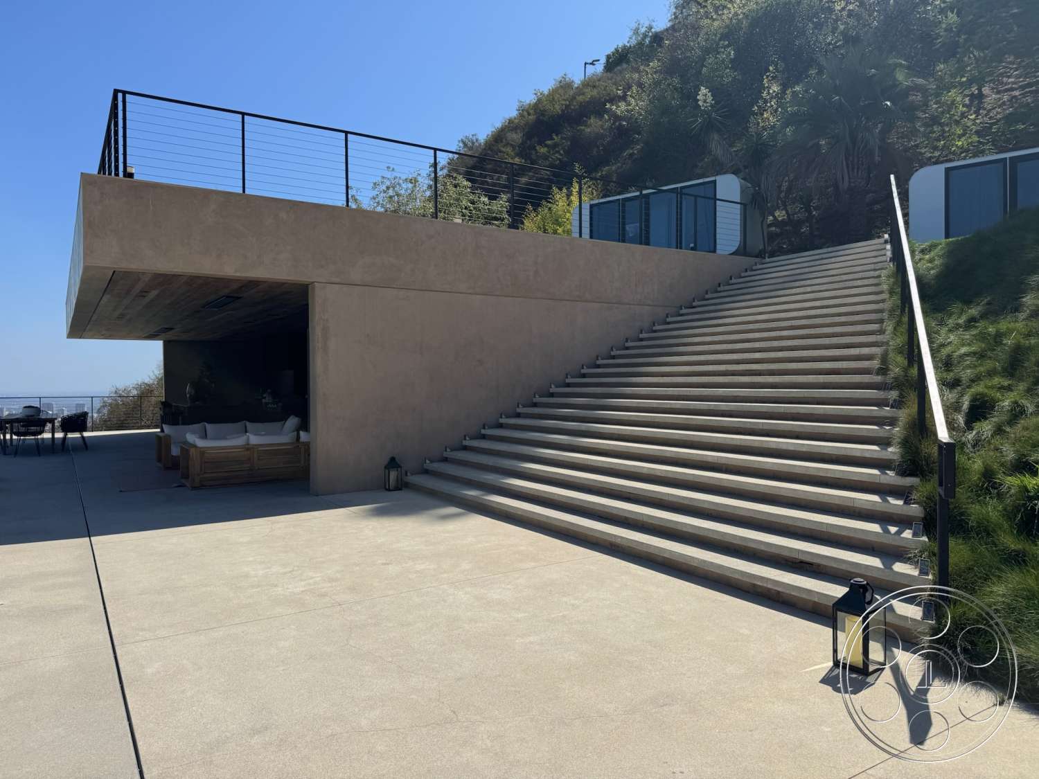 Modern 527 - exterior, exposed concrete walls, concrete steps, modern architectural style, flat roof design, concrete patio floor, open outdoor seating area, metal railing details, landscaped hillside setting