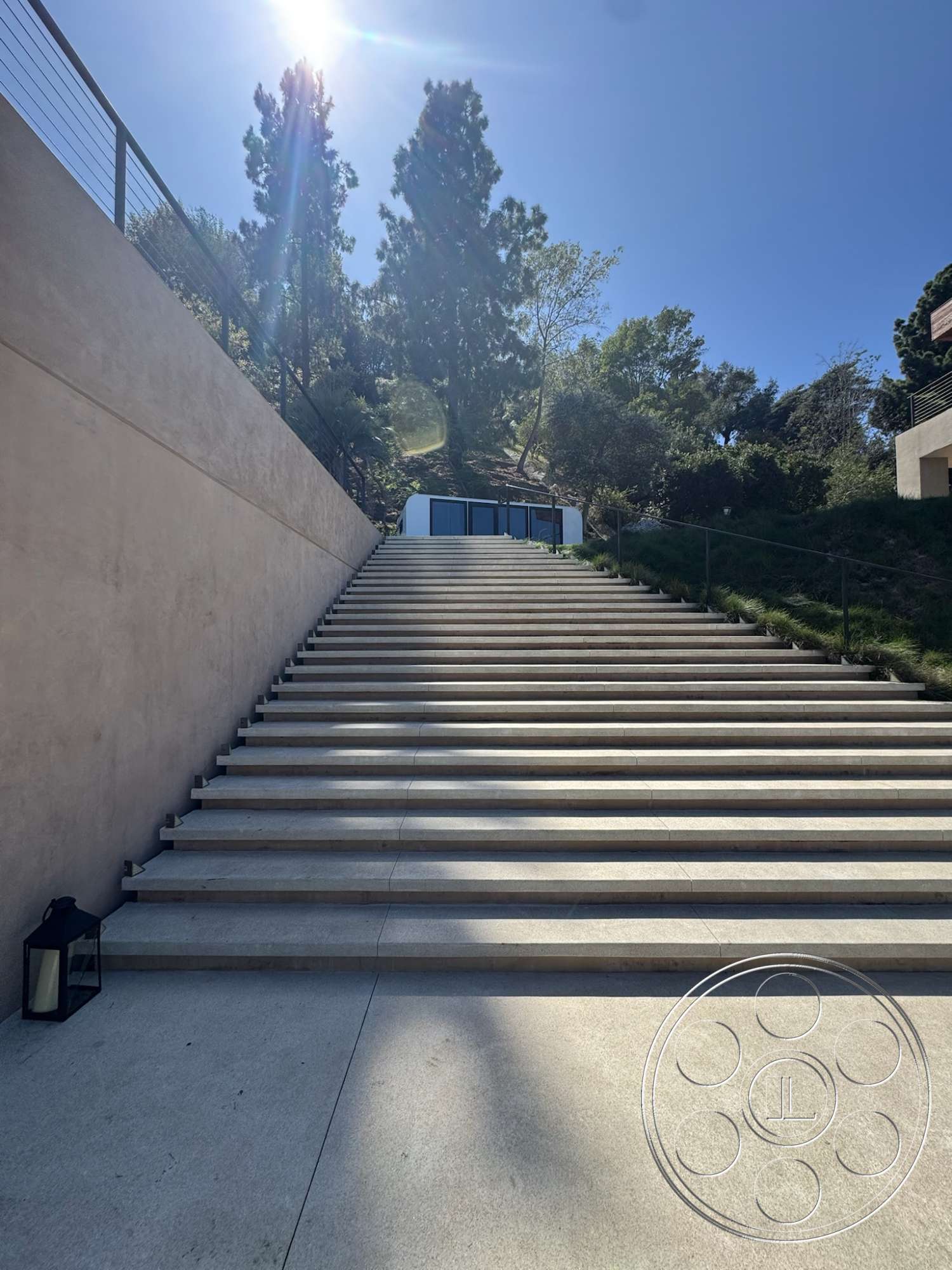 Modern 527 - exterior, modern architecture, glass railing, concrete stairs, landscaped hillside, natural sunlight, mid-century modern style, concrete retaining wall, rectangular steps, greenery surroundings