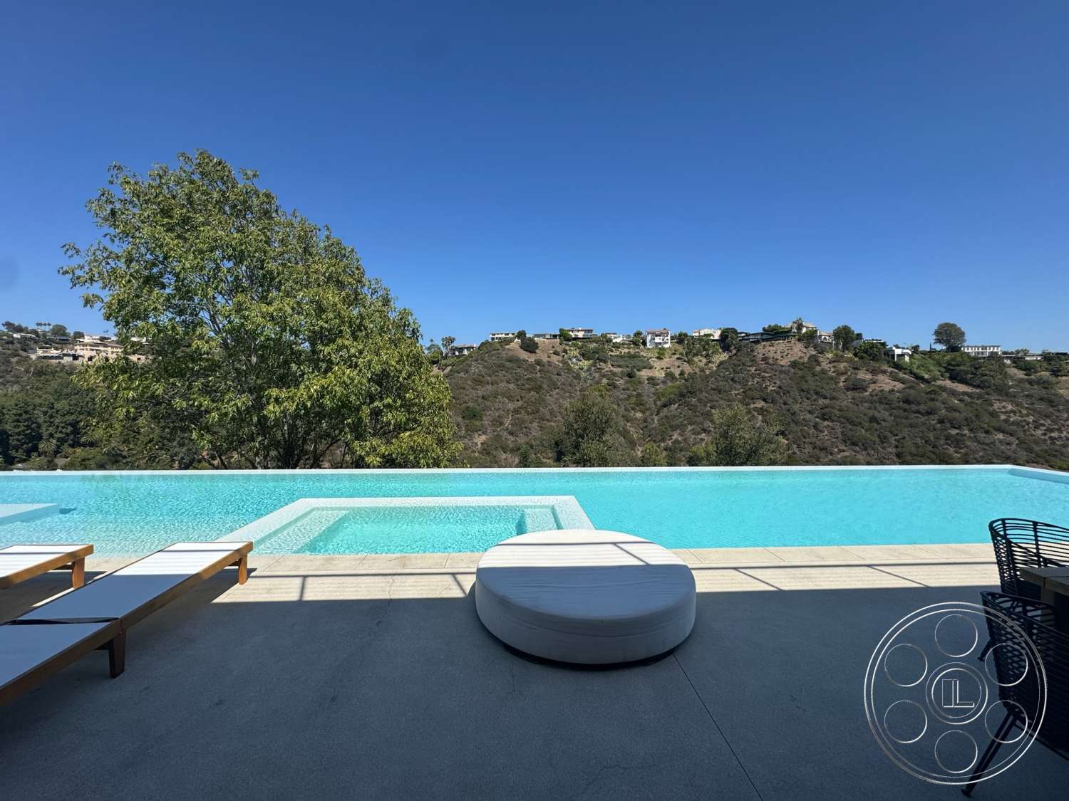 Modern 527 - exterior, landscaped hillside, infinity pool, luxury outdoor living, concrete patio floor, modern architectural design, white cushion seating, wooden sun loungers, rectangular spa, distant hillside view