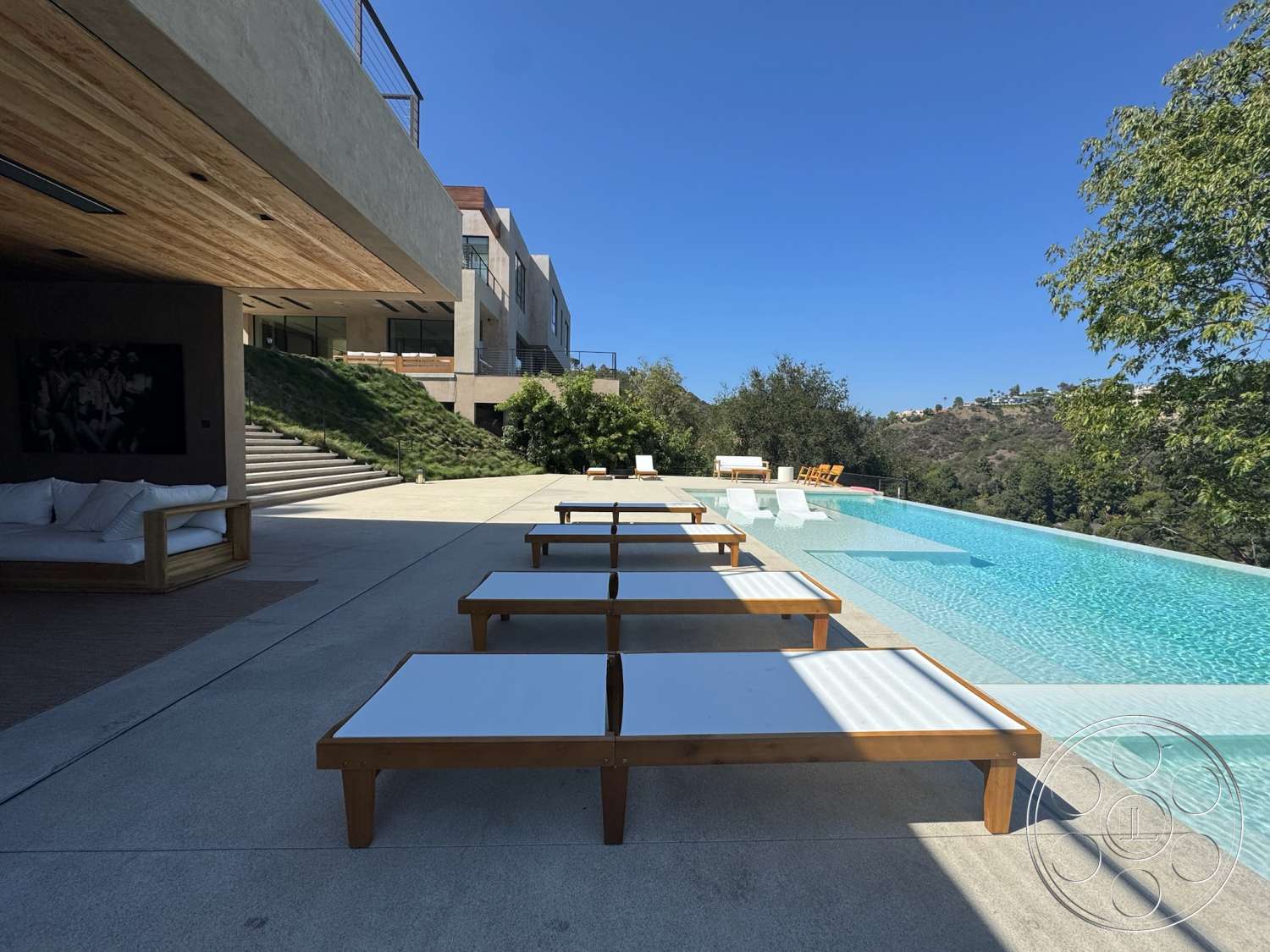 Modern 527 - exterior, outdoor seating area, glass railing, modern architectural style, landscaped hillside, infinity pool, wooden lounge chairs, residential pool area, sunny outdoor setting, concrete patio flooring, overhanging wood ceiling